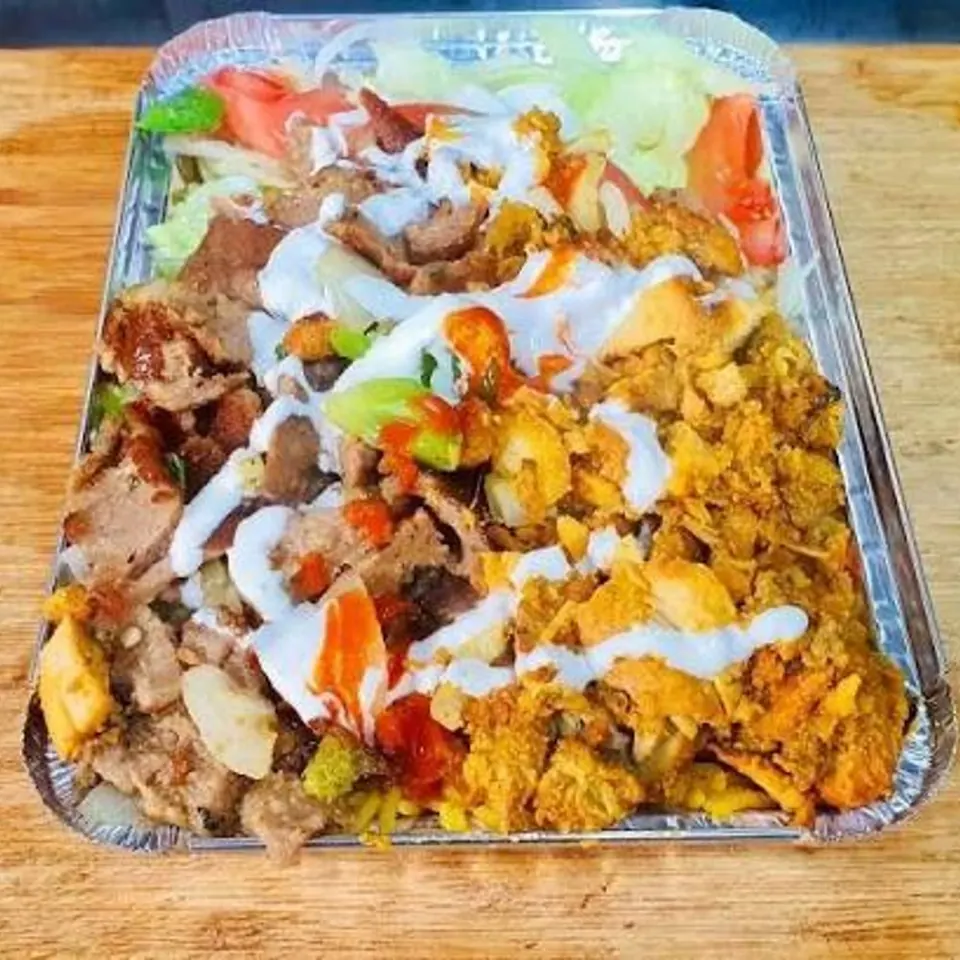 Chicken and lamb over rice with salad, white sauce, and hot sauce