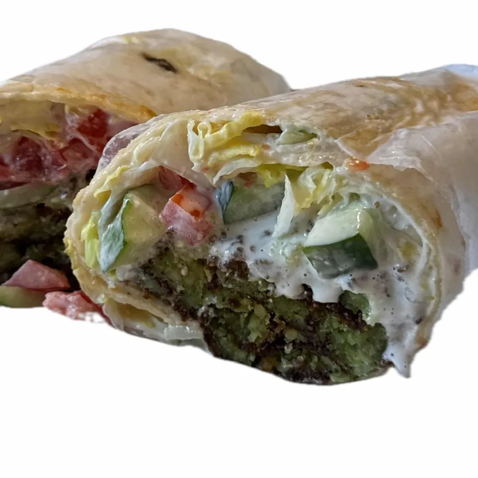 Falafel wrap cut open to show falafel, cucumber, tomato, and white sauce