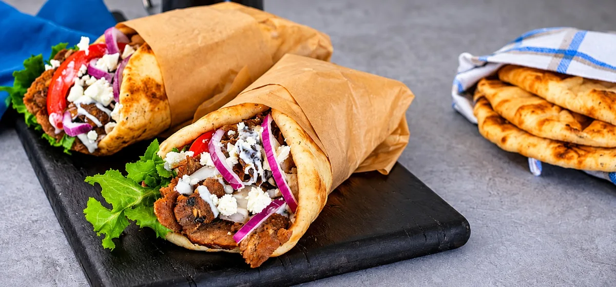 Lamb gyro in grilled pita with lettuce, tomato, cucumber, and white sauce