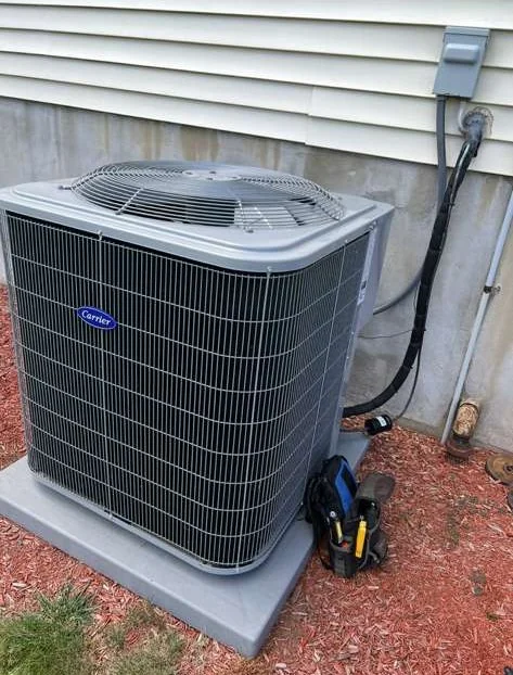 Carrier residential AC condenser installation beside a home