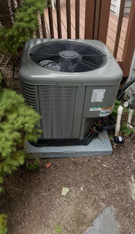 Residential outdoor AC condenser unit beside a home